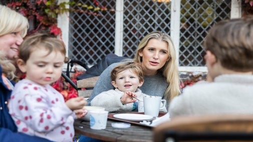 Visitors enjoying their refreshments outside in the seating area of the tea room at Rufford Old Hall, Lancashire